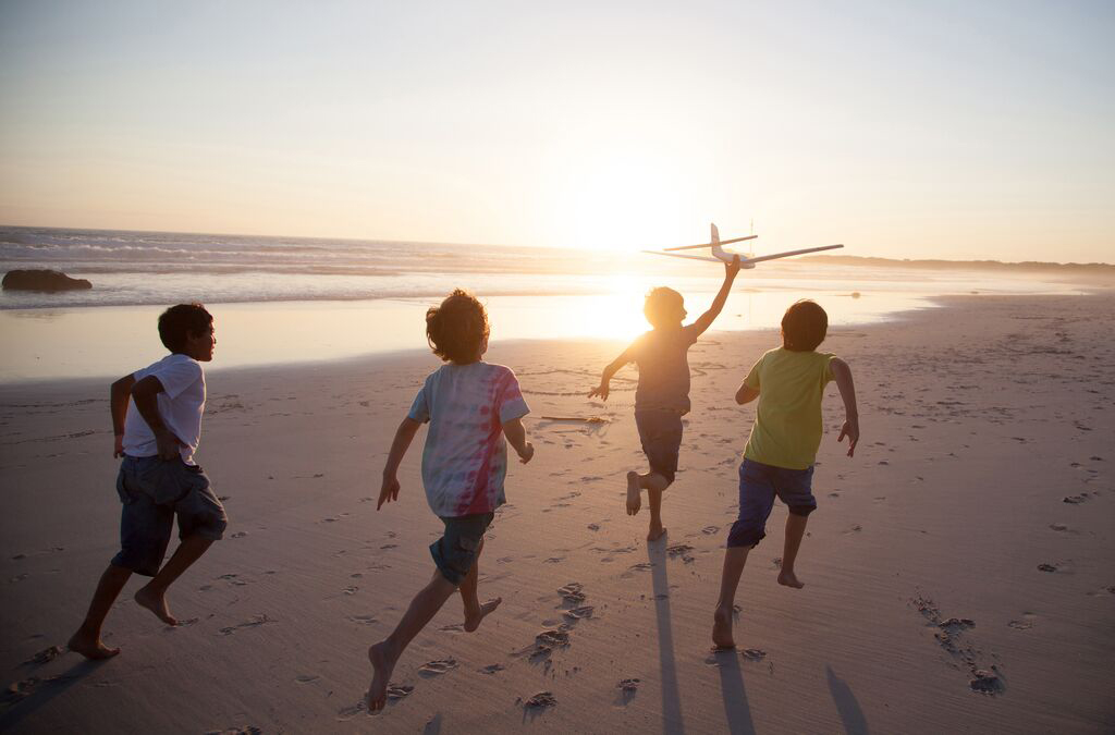 Children running together along a beach at sunset